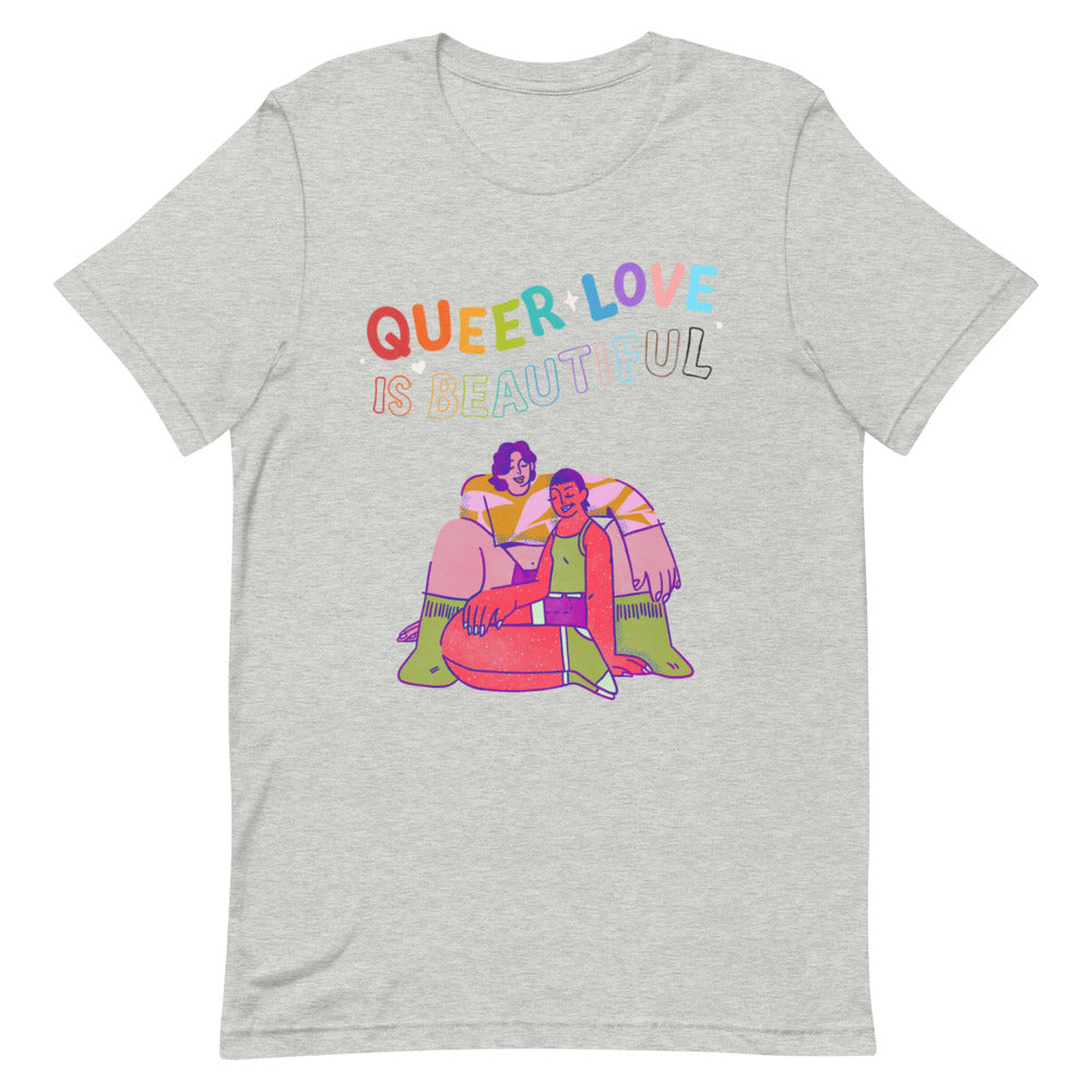 Front view of a heather-gray T-shirt reading “QUEER LOVE IS BEAUTIFUL,” with a colorful illustration of two people embracing.