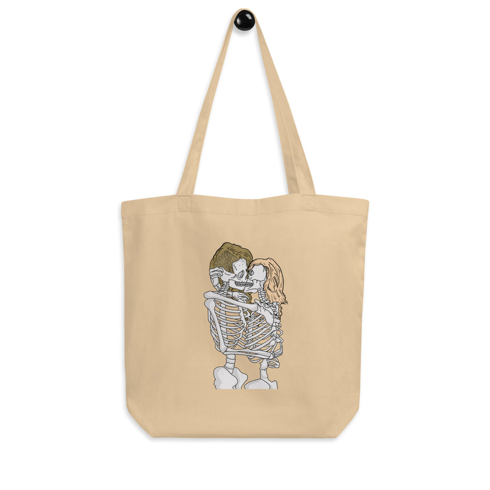 Front view of a beige tote bag printed with two skeletons kissing and embracing