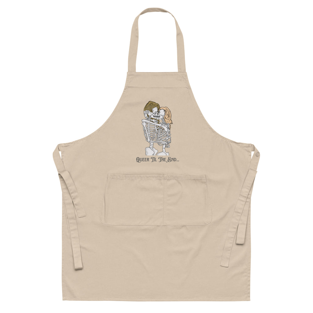 Front view of a beige apron with a skeleton couple kissing and “Queer Til The End...” text