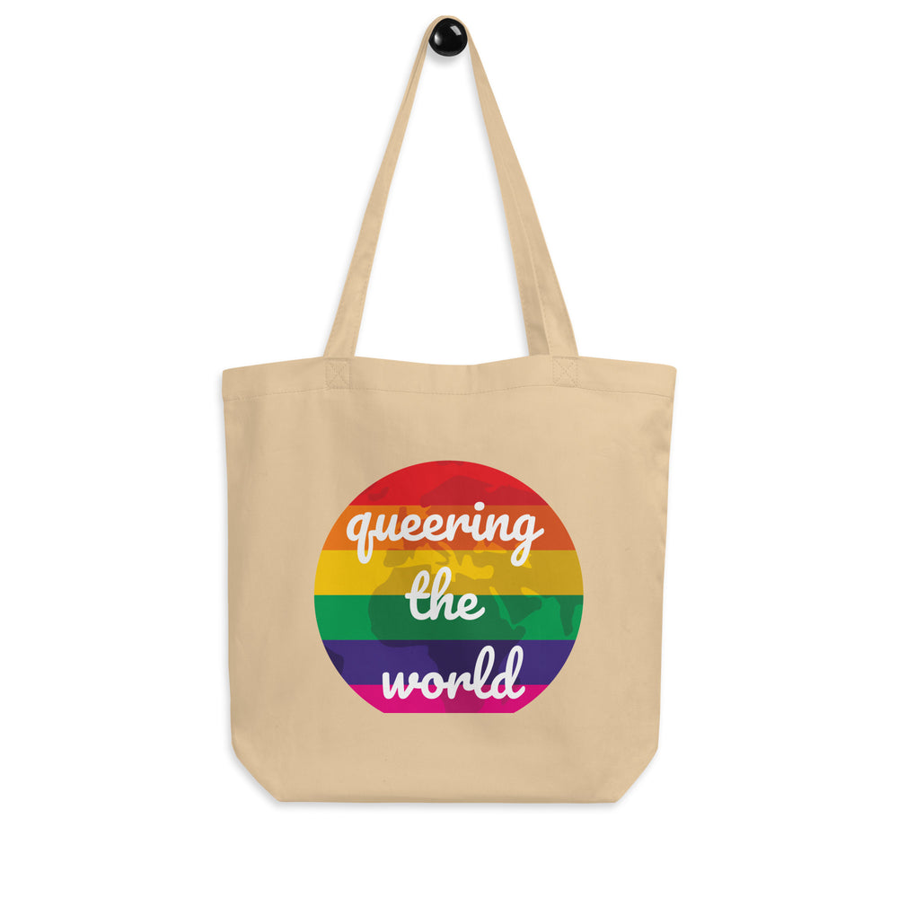 Front view of a natural canvas tote with a rainbow circle reading “queering the world”