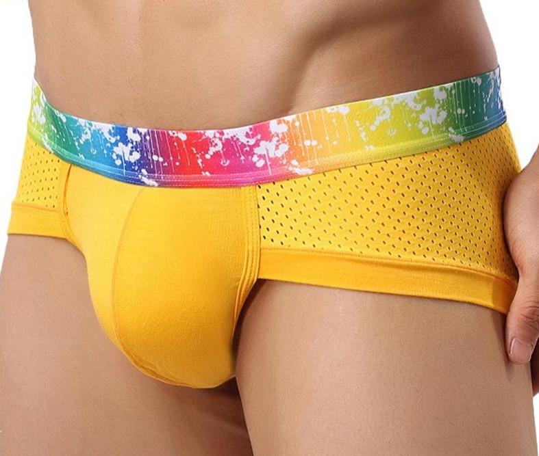 Close-up of yellow sports briefs with perforated mesh panels and a rainbow paint-splatter waistband