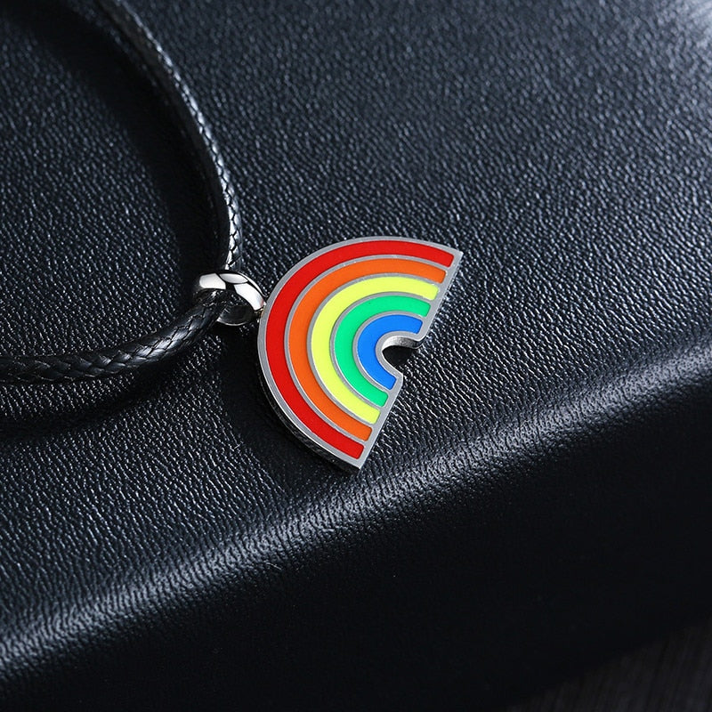 Close-up of a rainbow-striped pendant on a black braided cord over black textured fabric
