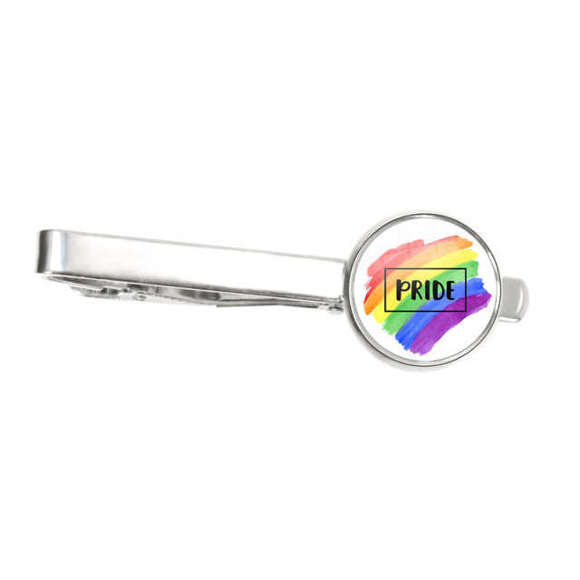 Silver tie clip with a round rainbow brushstroke badge reading “PRIDE”