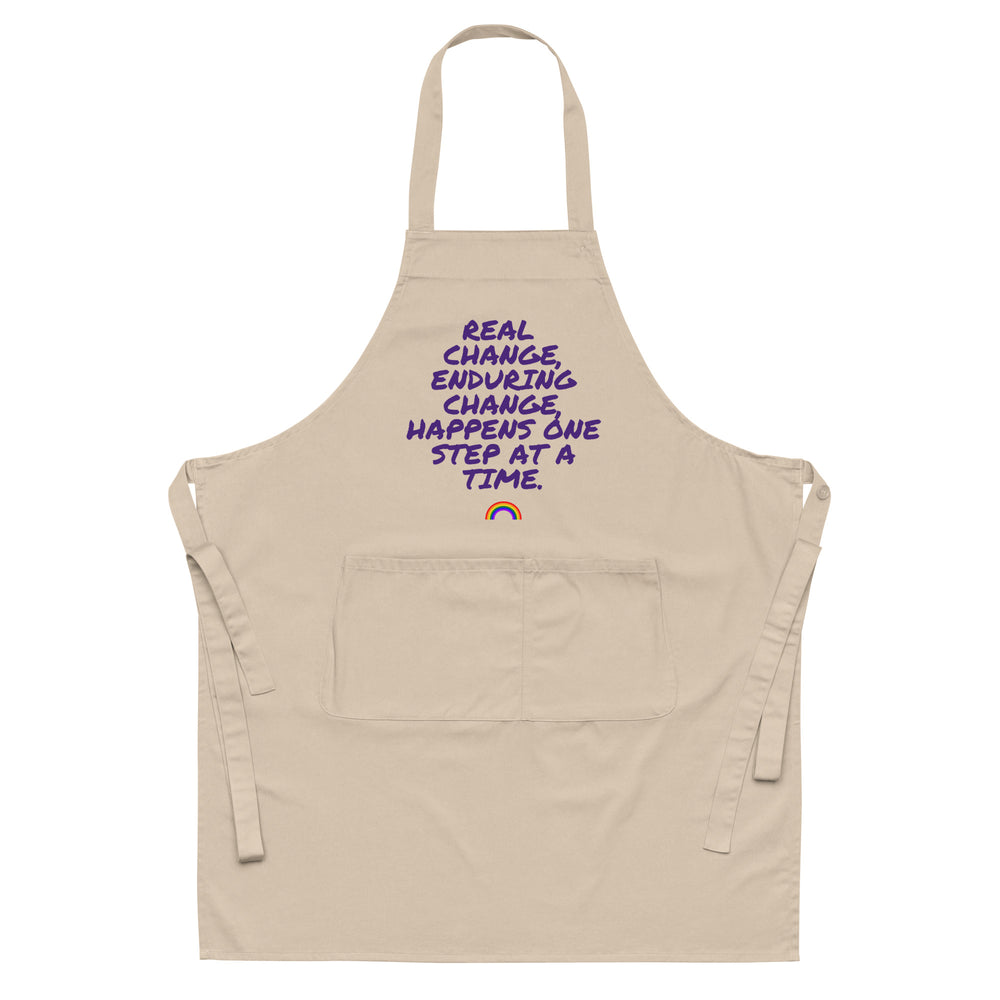 Front view of a beige apron with purple text, a rainbow, and a large front pocket