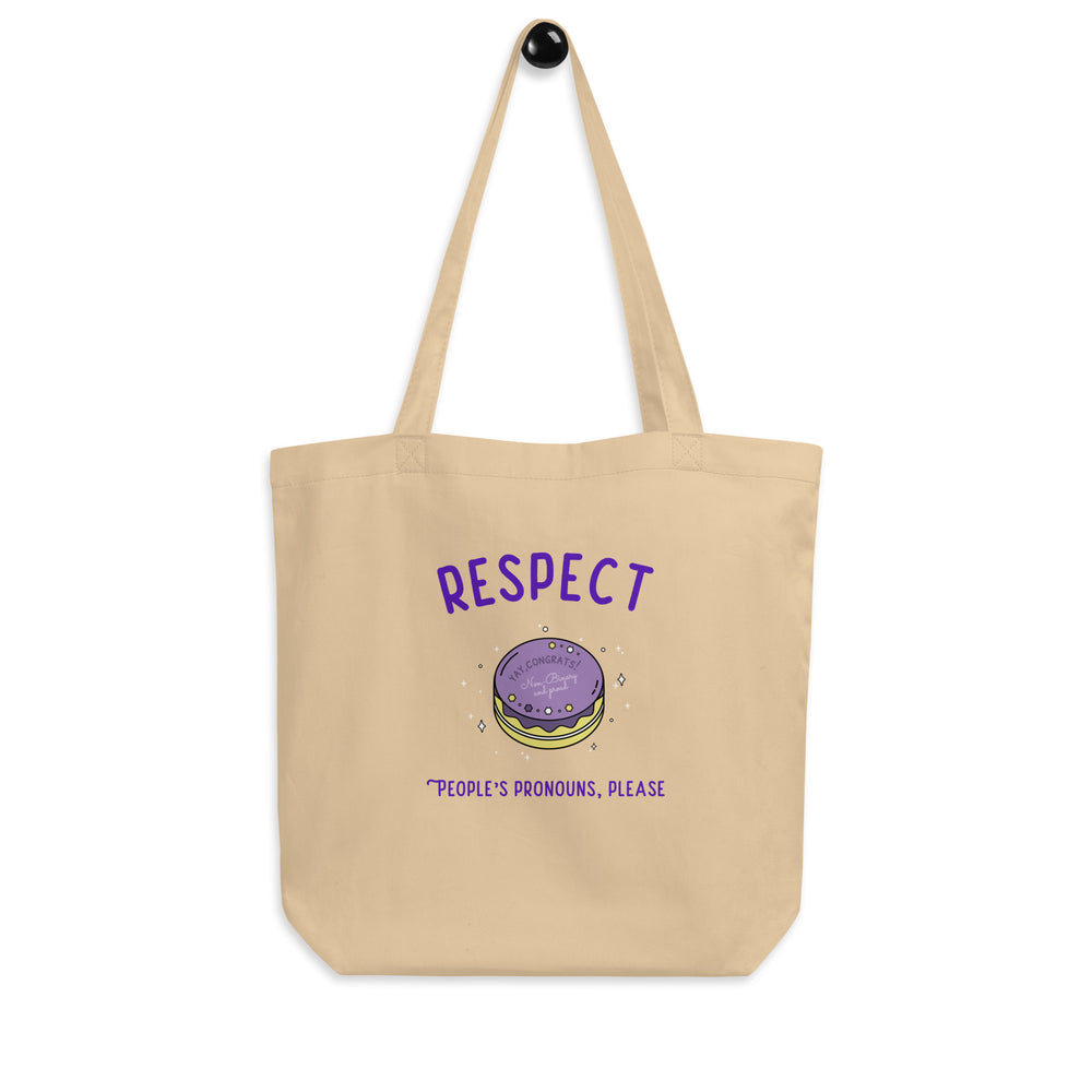 Natural canvas tote bag reading “RESPECT PEOPLE’S PRONOUNS, PLEASE,” with a cake illustration