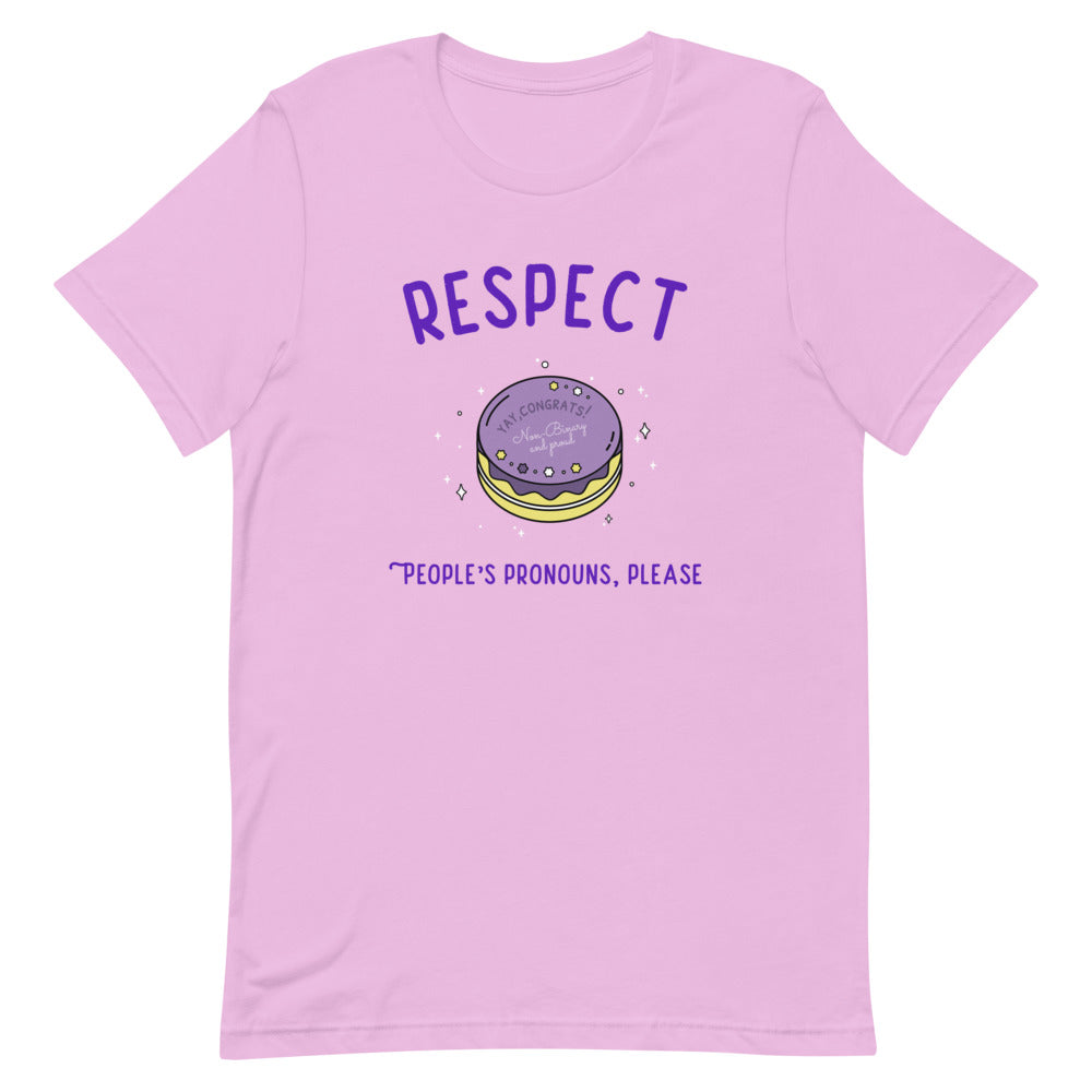 Flat-lay lilac T-shirt reading “RESPECT PEOPLE’S PRONOUNS, PLEASE” with a cake graphic