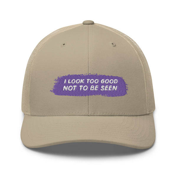Front view of a beige trucker cap with purple patch reading “I LOOK TOO GOOD NOT TO BE SEEN”