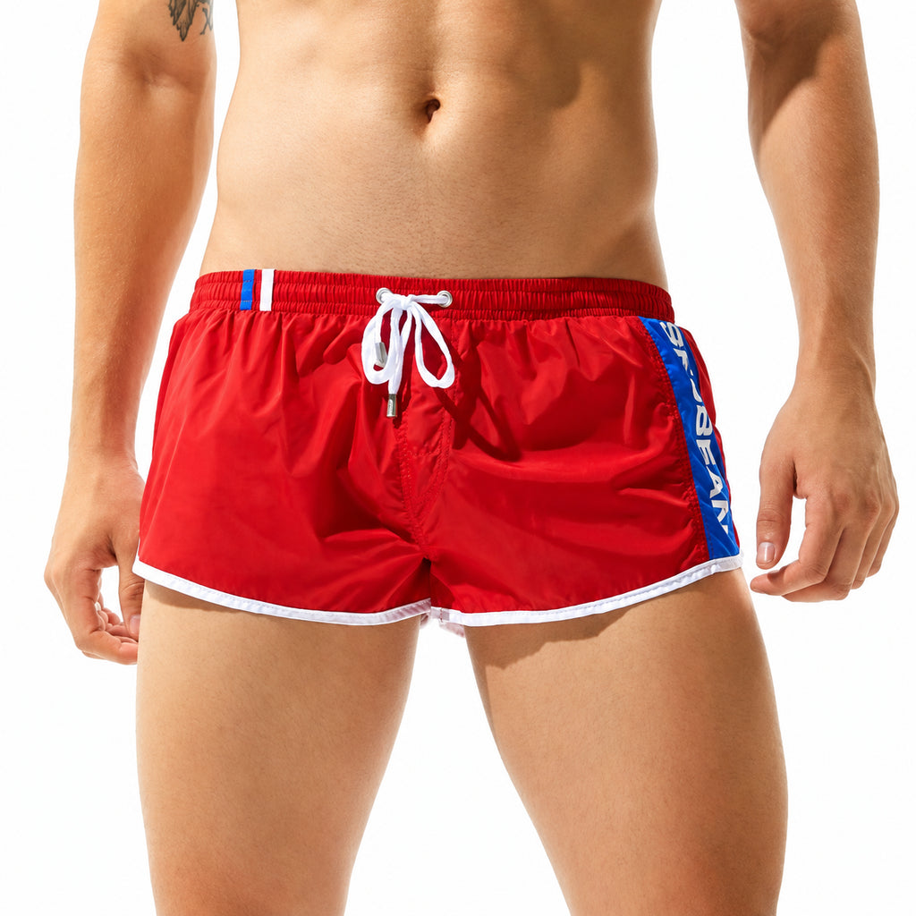 Front view of a model wearing bright red men's gym shorts with white trim and blue side panels