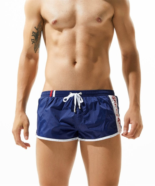 Front view of a shirtless model wearing navy blue gym shorts with white trim and drawstring