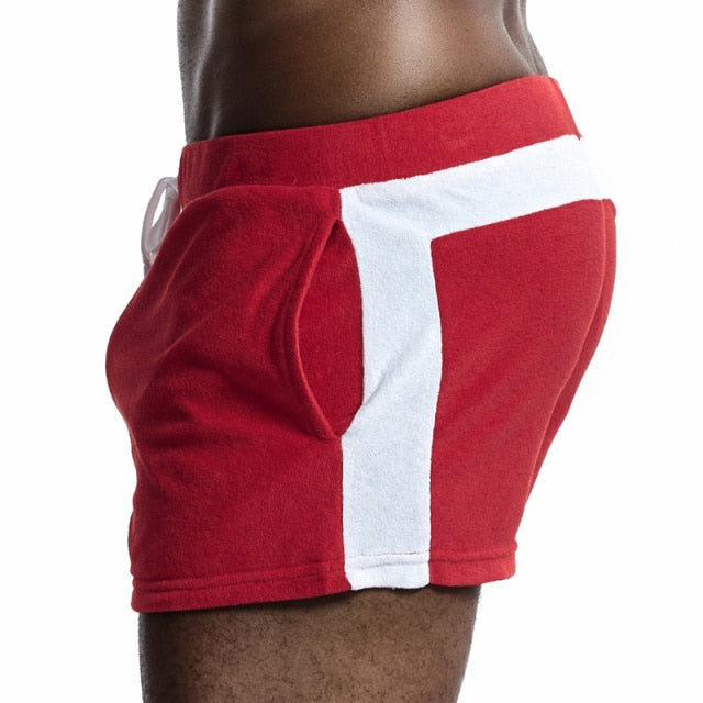 Side-back close-up of a model wearing red velour shorts with a white stripe