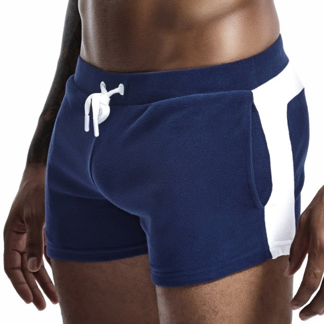 Cropped model wearing navy velour shorts with white side panels and drawstring