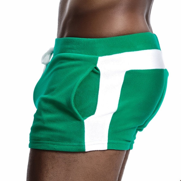 Close rear-side view of a model wearing green velour shorts with a white stripe