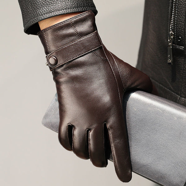 Close-up of a dark brown leather glove with a buckled wrist strap on a gray-sleeved arm