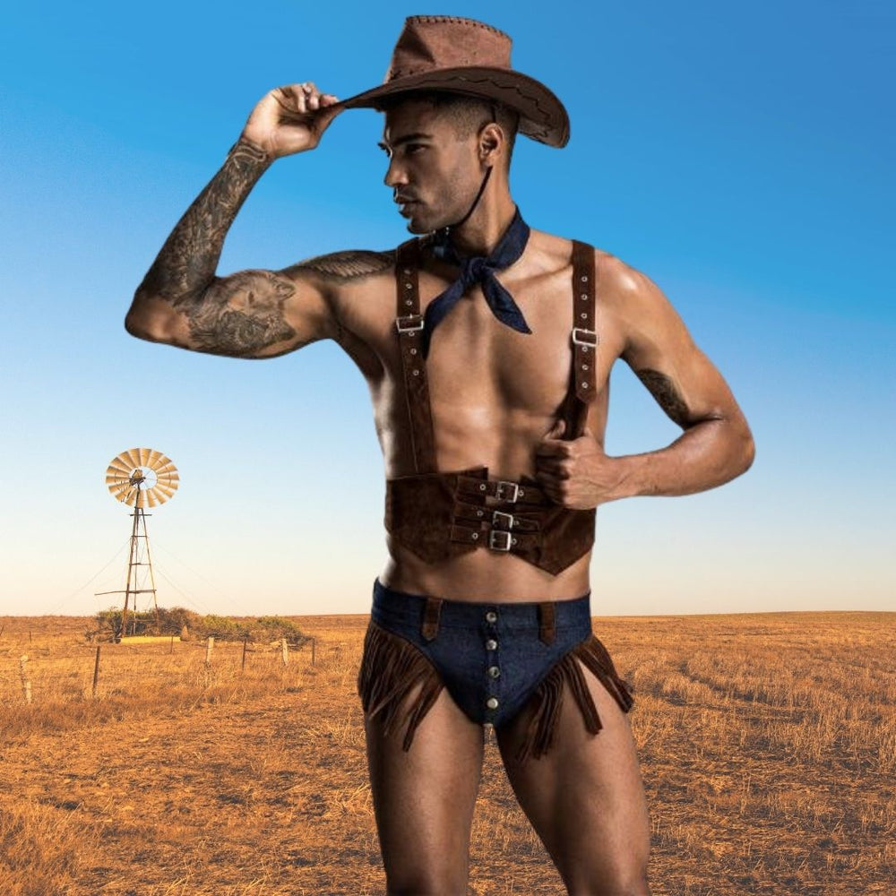 Model wearing a brown cowboy hat, leather-look harness and fringed chaps in a ranch landscape