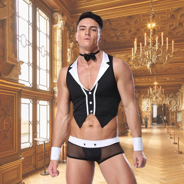 Model wearing a black-and-white male maid costume with bow tie and mesh shorts in an ornate room