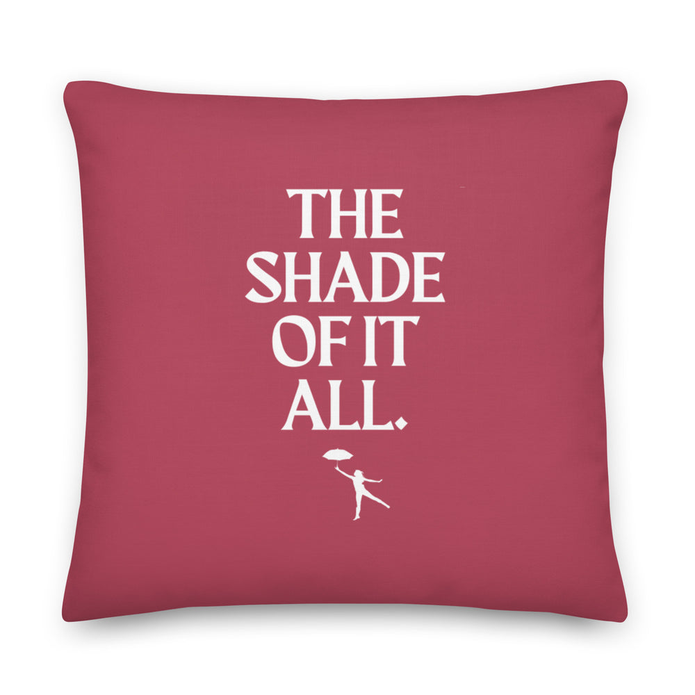 Square burgundy pillow with white “THE SHADE OF IT ALL.” lettering and umbrella figure