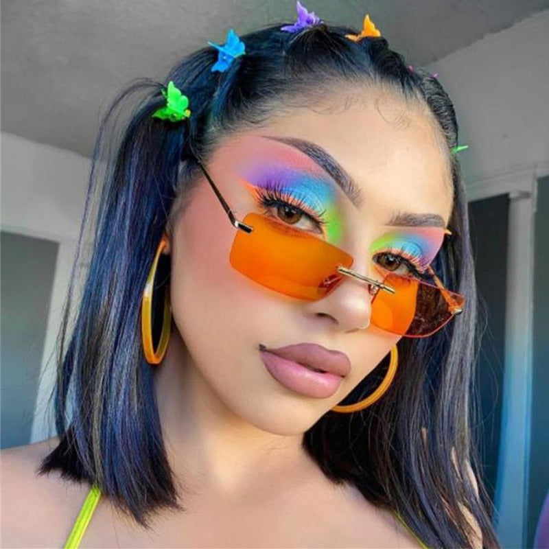 Close-up model wearing rimless orange gradient sunglasses with narrow rectangular lenses