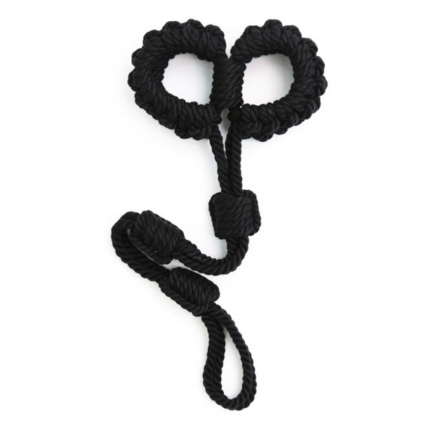 Black braided rope shibari handcuffs arranged in a heart-like shape on white