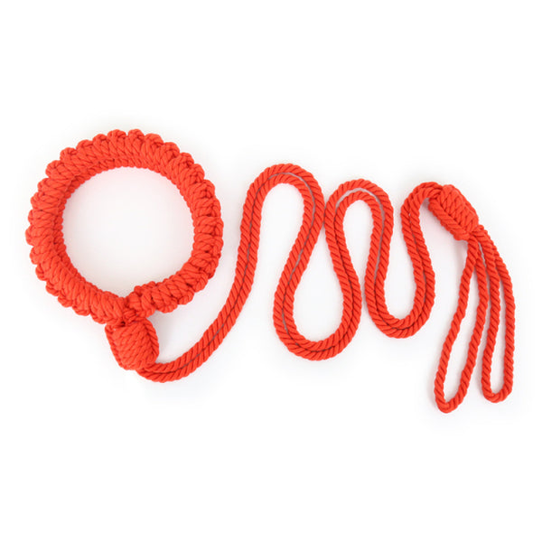 Bright red braided rope handcuff loop arranged in loose coils on a white background