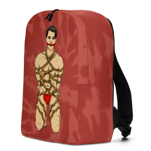 Red backpack with black straps, featuring an illustrated bound figure in red underwear