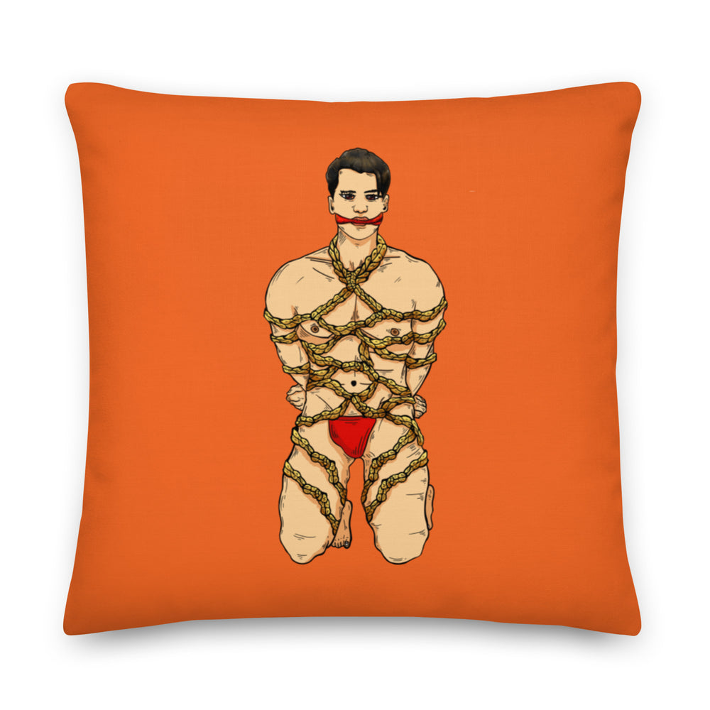 Orange square pillow featuring an illustrated man bound in decorative rope and wearing red underwear