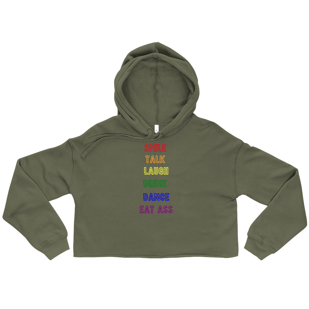 Olive cropped hoodie laid flat with rainbow text reading “SMILE TALK LAUGH DRINK DANCE EAT ASS”
