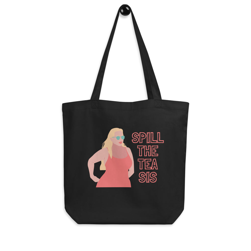 Front view of a black tote bag reading “SPILL THE TEA SIS” beside a sunglasses-wearing woman