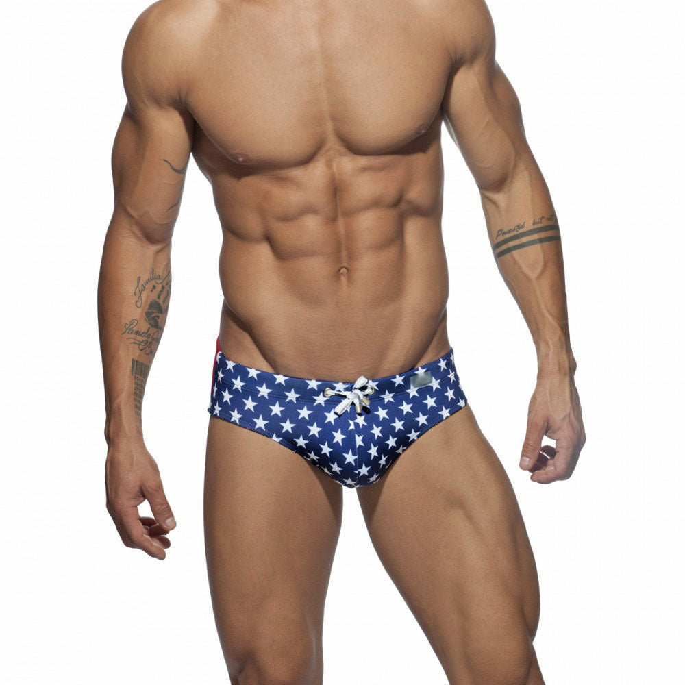 Front view of a model wearing blue star-print swim briefs with a white drawstring