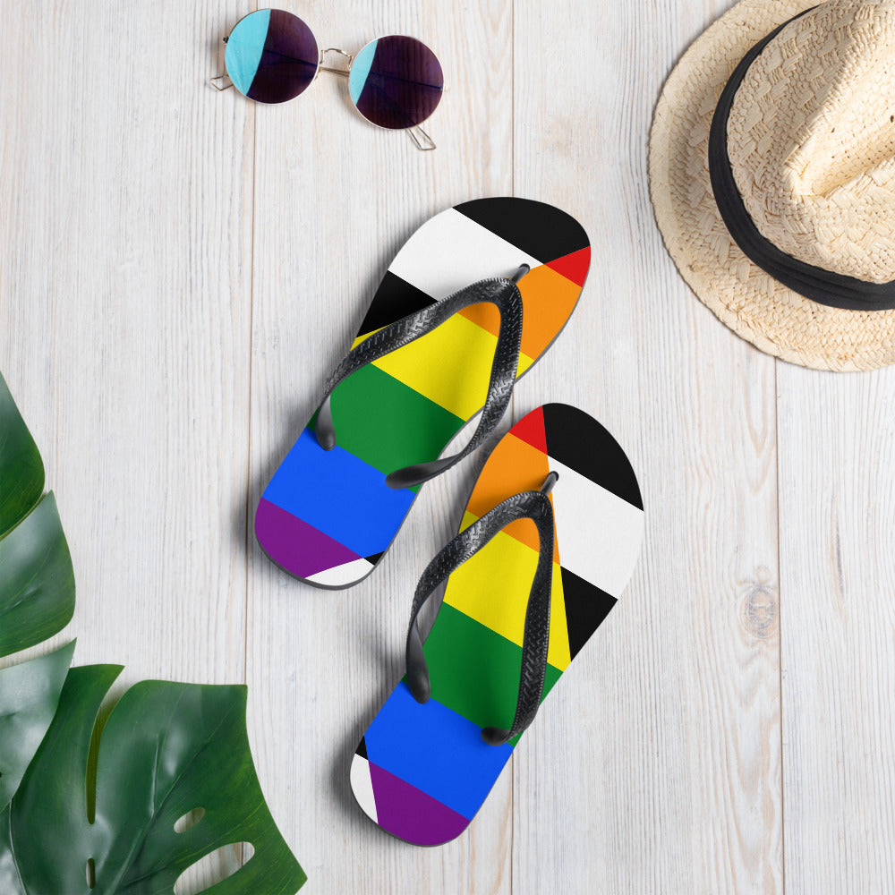 Straight Ally flip-flops with black-and-white, rainbow, and orange geometric flag-style stripes