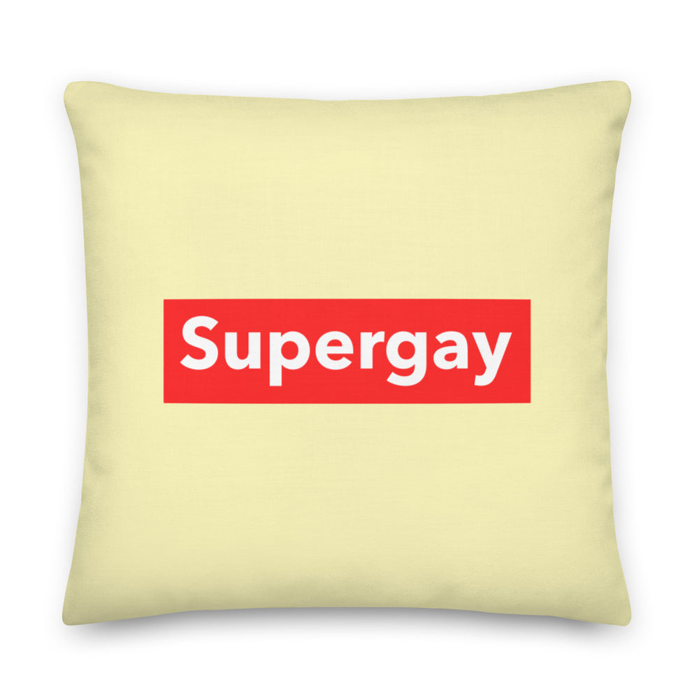 Pale yellow square pillow with a red rectangle reading “Supergay” in white