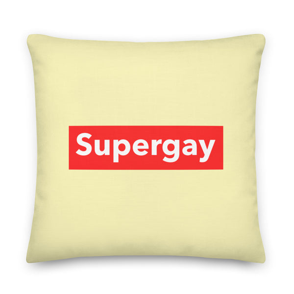 Pale yellow square pillow with a red rectangle reading “Supergay” in white