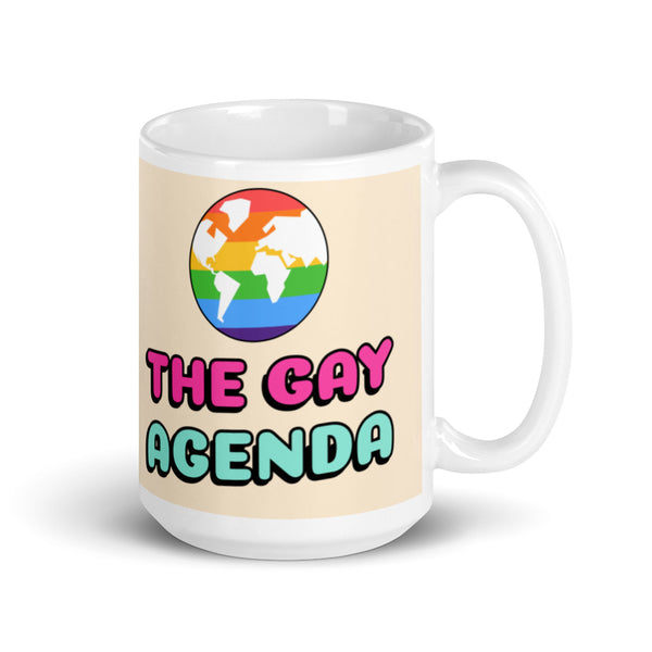 White mug reading “THE GAY AGENDA,” with a rainbow globe graphic and right-side handle