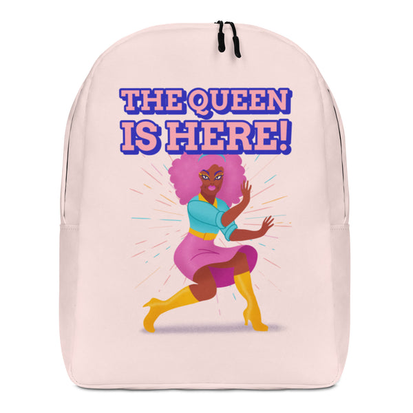 Front view of a pale pink backpack reading “THE QUEEN IS HERE!” above a colorful dancing woman