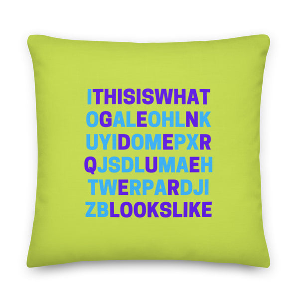 Front-facing lime-green pillow with blue and purple scrambled-letter text reading “This is what genderqueer looks like.”