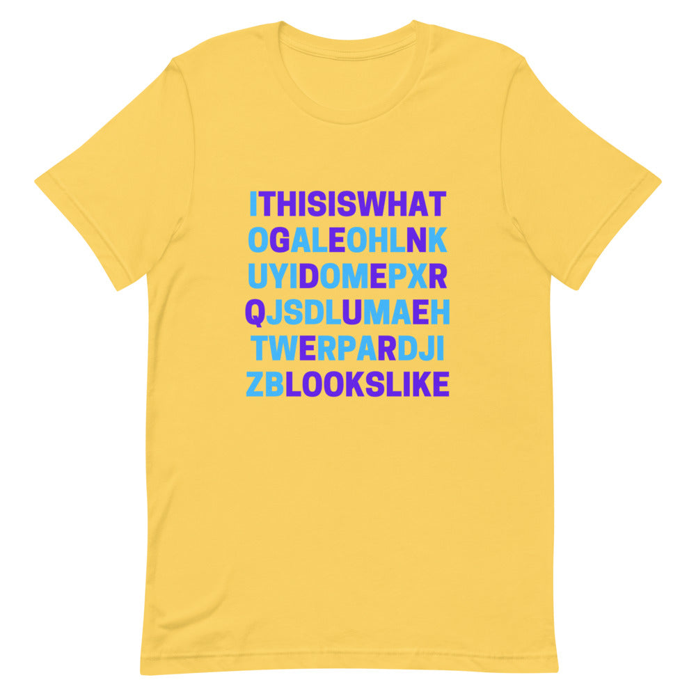 Yellow T-shirt with bold blue and purple block lettering reading “This is what genderqueer looks like”