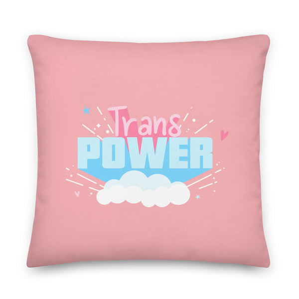 Pink square pillow with a colorful “Trans Power” graphic, clouds, stars, and hearts