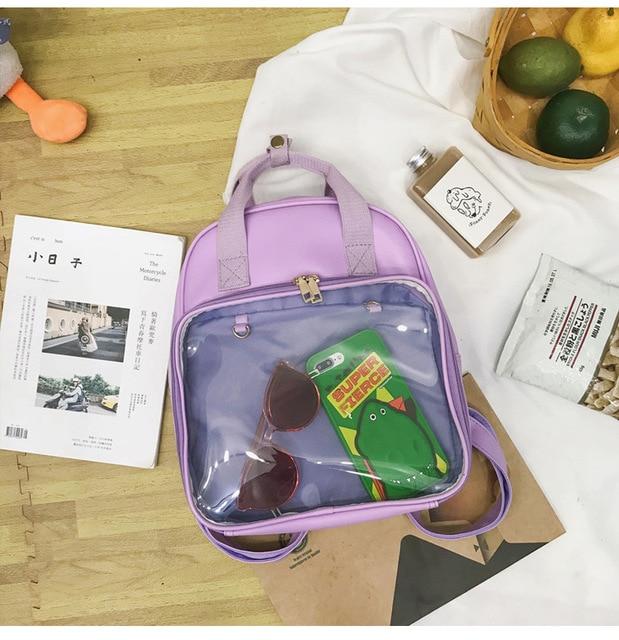 Lavender backpack with a clear front pocket displaying sunglasses and colorful accessories