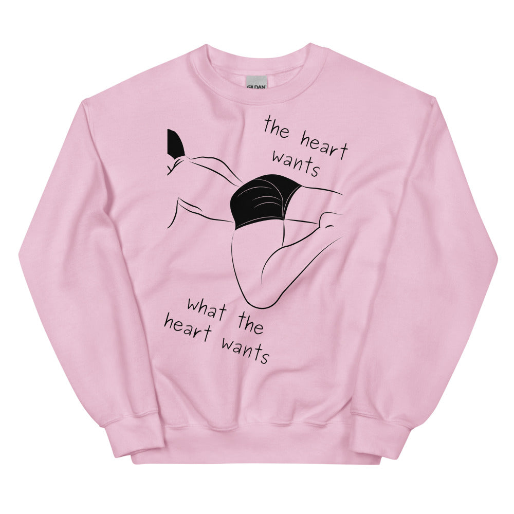 Pink crewneck sweatshirt with black line-art figure and “the heart wants what the heart wants” text