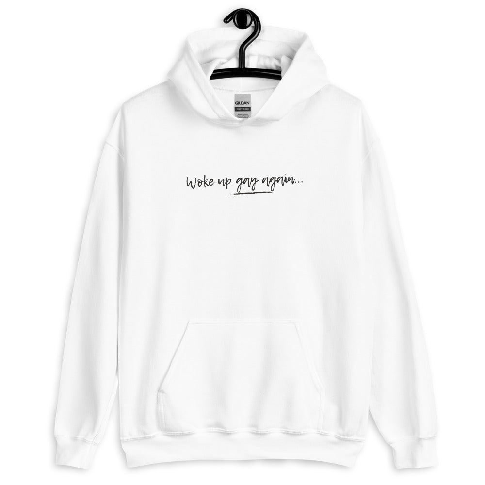 Front view of a white hoodie reading “Woke up gay again…” in black script