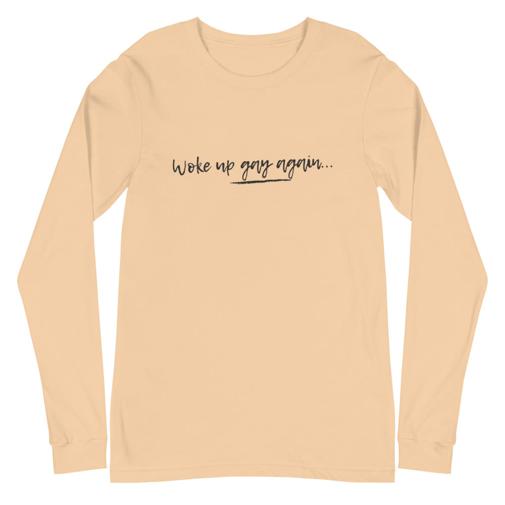 Front view of a sand-colored long-sleeve shirt reading “Woke up gay again…”