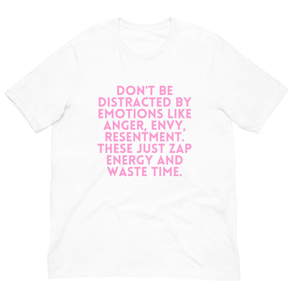 Flat-lay white T-shirt with pink text: “DON’T BE DISTRACTED BY EMOTIONS LIKE ANGER, ENVY, RESENTMENT. THESE JUST ZAP ENERG...
