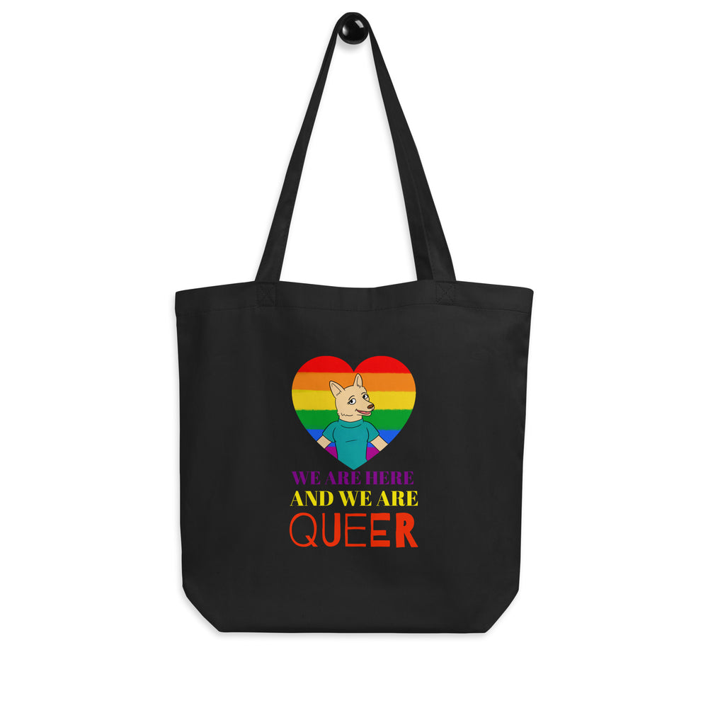Black tote bag with a rainbow heart, cartoon animal, and “WE ARE HERE AND WE ARE QUEER” text