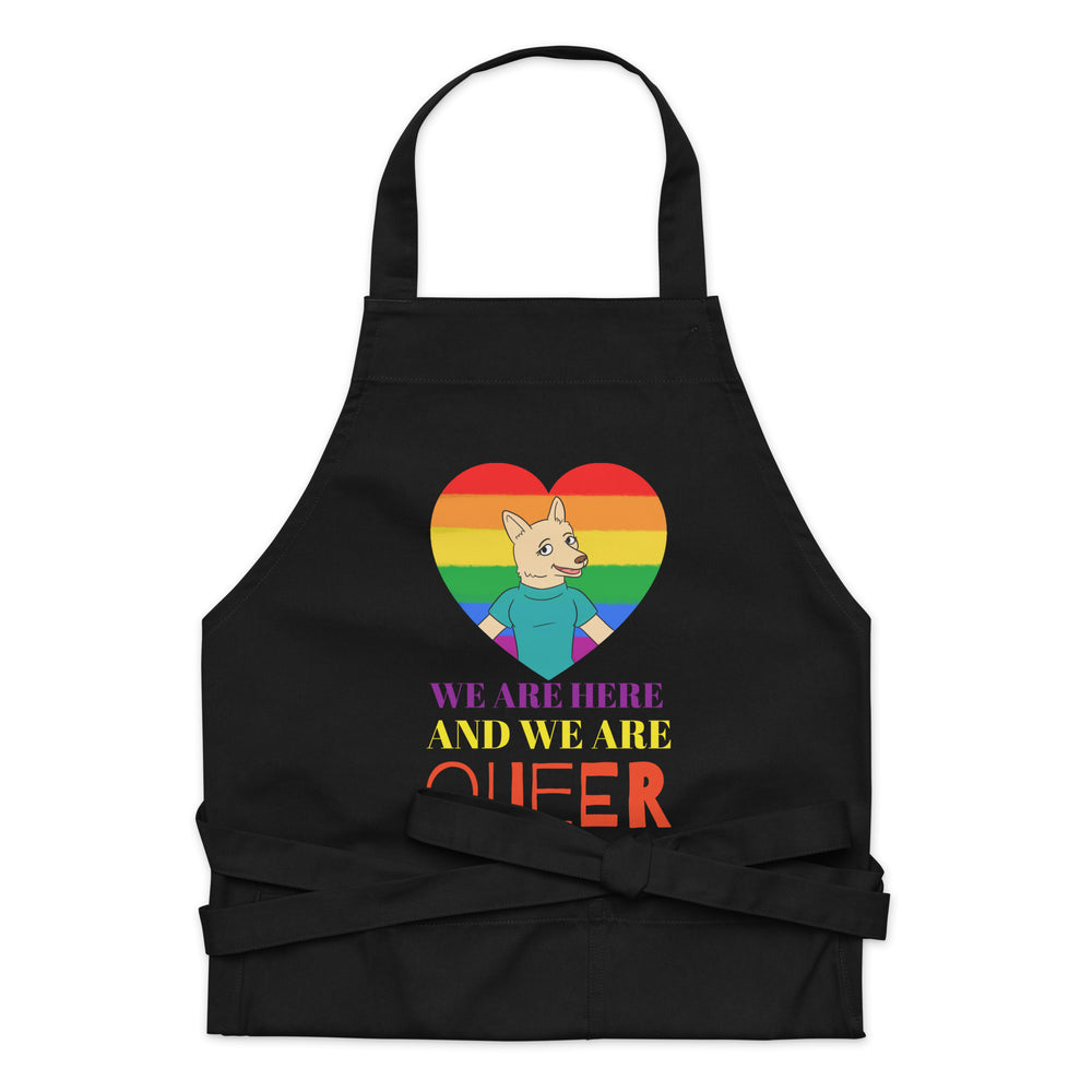 Front view of a black apron with a rainbow heart, cartoon fox, and “WE ARE HERE AND WE ARE QUEER” text