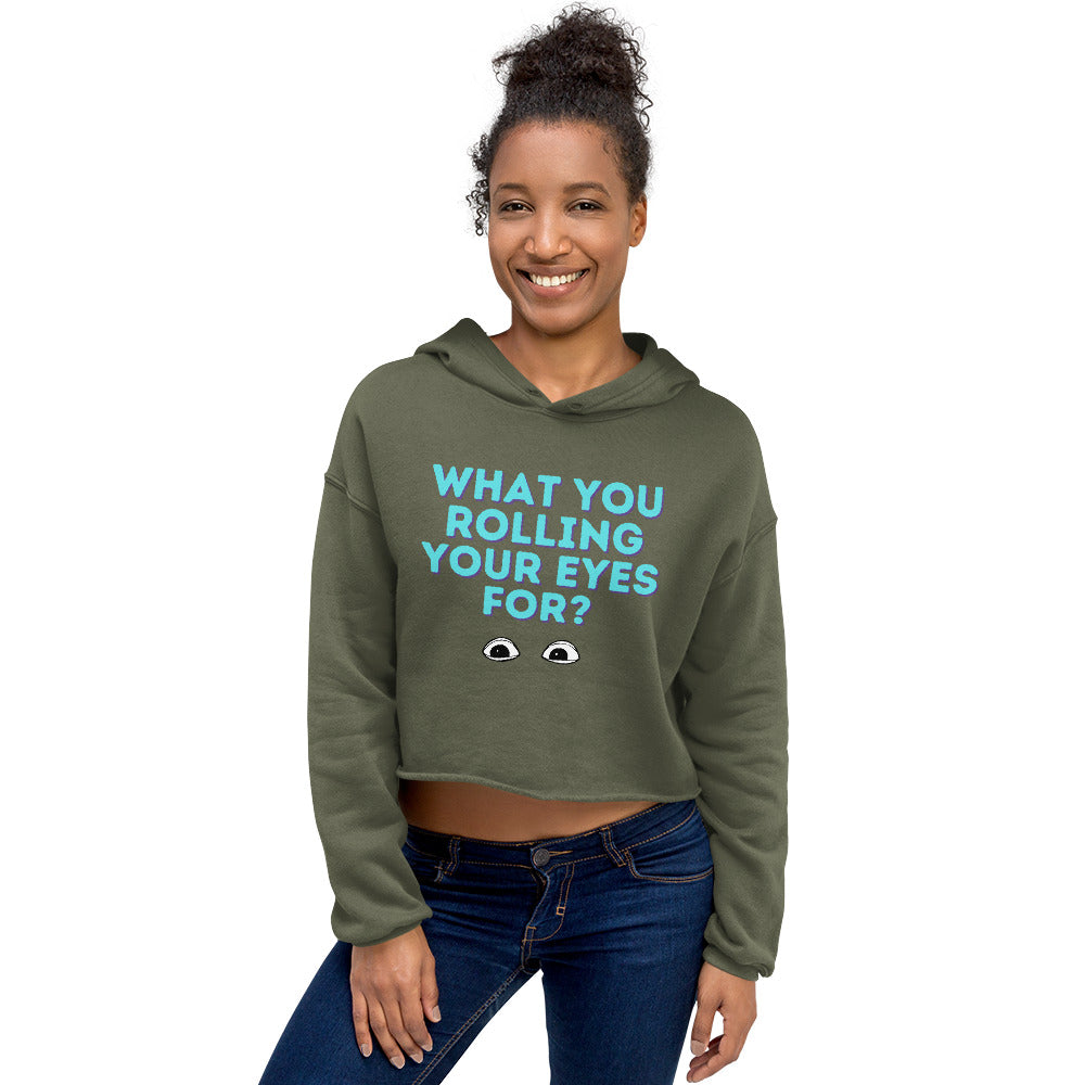 Model wearing an olive green cropped hoodie reading “WHAT YOU ROLLING YOUR EYES FOR?”