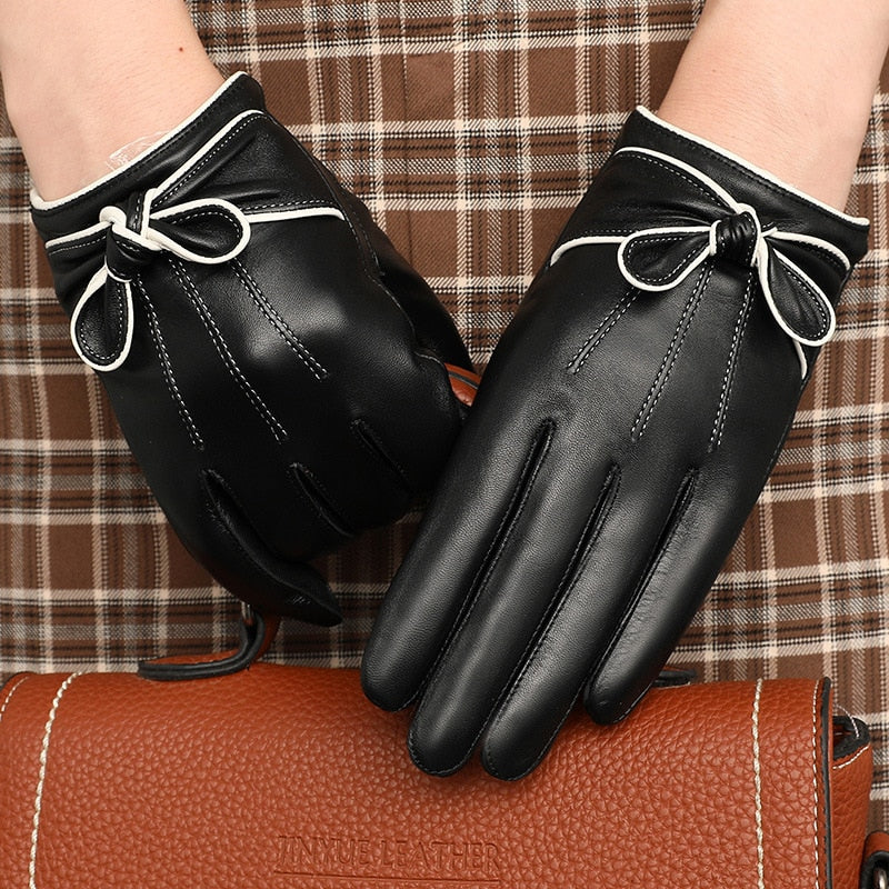 Pair of black gloves with white-trimmed bow cuffs on a plaid background