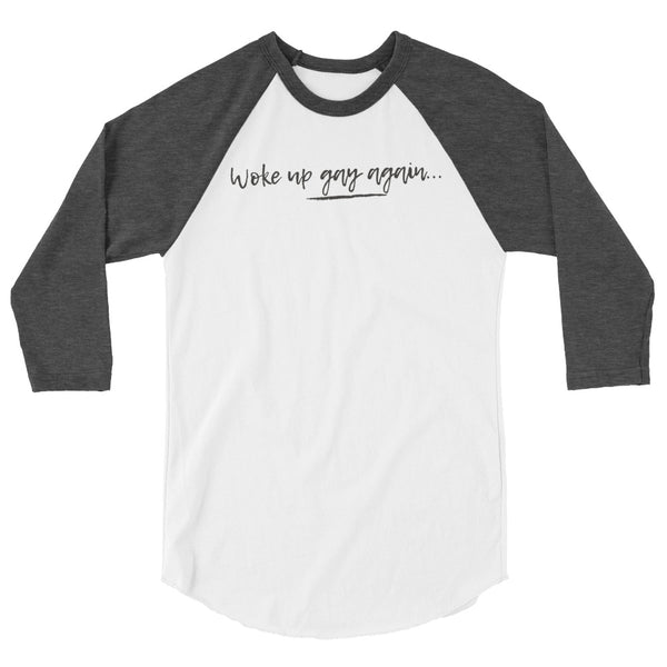 Front view of a white raglan shirt with charcoal sleeves reading “Woke up gay again...”