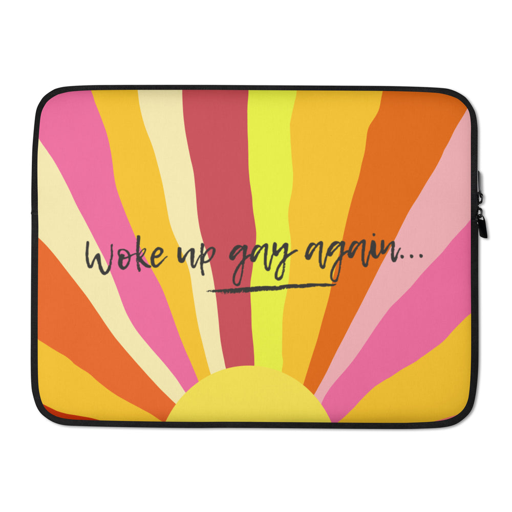 Front view of a laptop sleeve with rainbow rays and “woke up gay again...” text