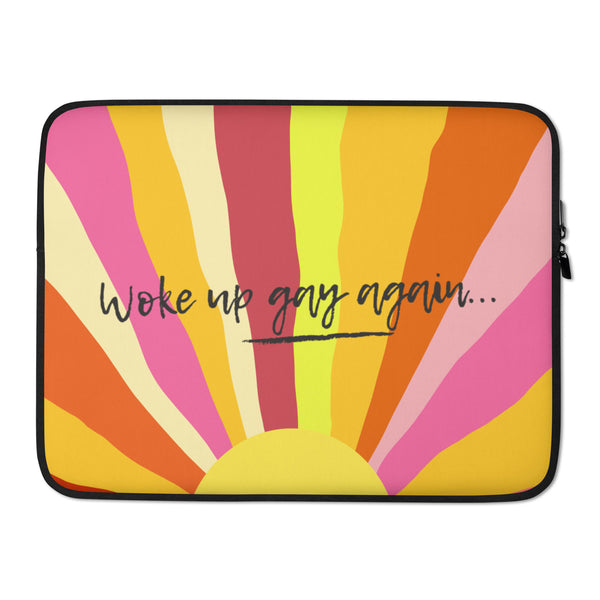 Front view of a laptop sleeve with rainbow rays and “woke up gay again...” text