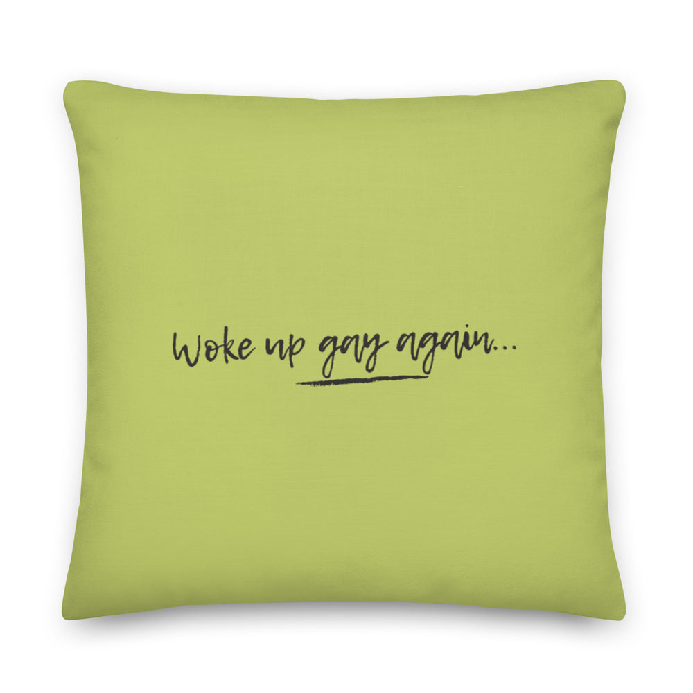 Front-facing lime green square pillow reading “woke up gay again…” in black script