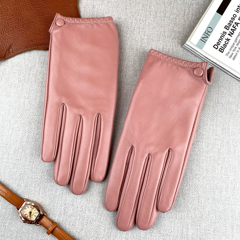 Pair of pink leather gloves arranged on a light fabric surface